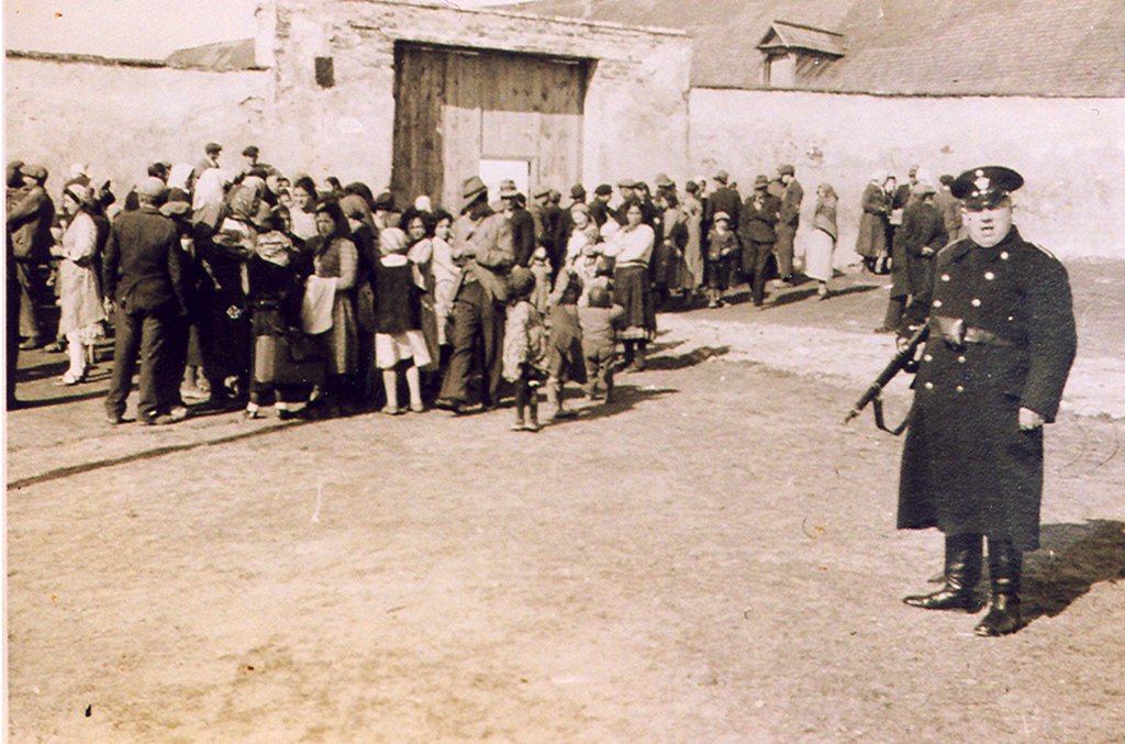 Angehöriger der Wiener Kriminalpolizei bei der Bewachung der ins Lager Lackenbach deportierten Roma Familien. Aufgenommen am 23.11.1940, am Tag der Eröffnung des Lagers Lackenbach.